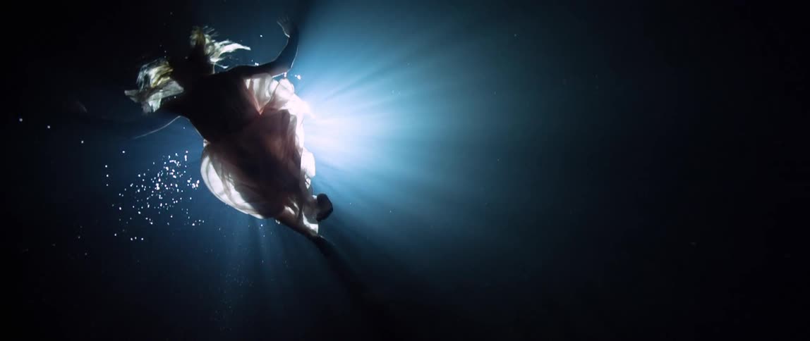A white woman in a dress swims underwater