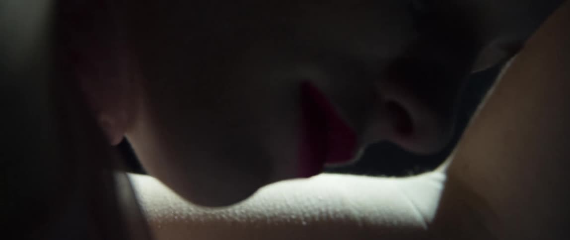 A blonde woman floats underwater wearing bright lipstick and jewelry