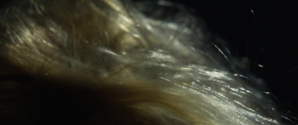 Blonde hair floats underwater in the dark with a light shining down