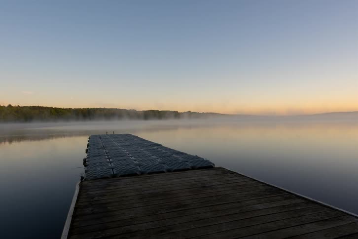 Clouds float over a dock and lake