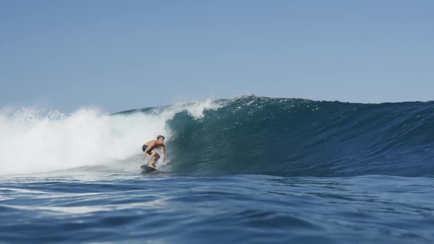 A man is surfing on a large wave