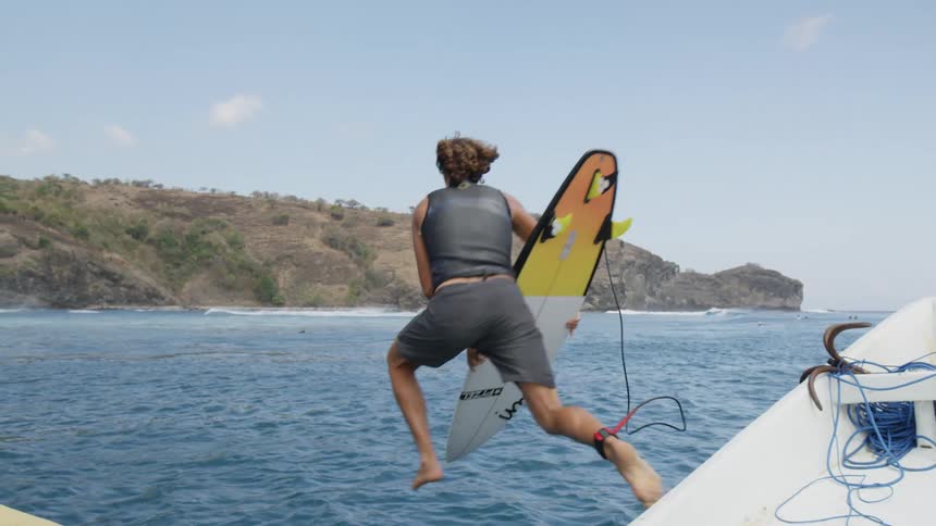 A man jumps off the boat with his surfboard