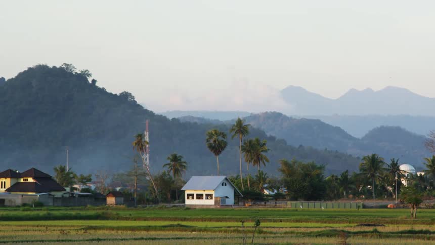 Small village sits near the mountains as a recreational vehicle travels in the distance
