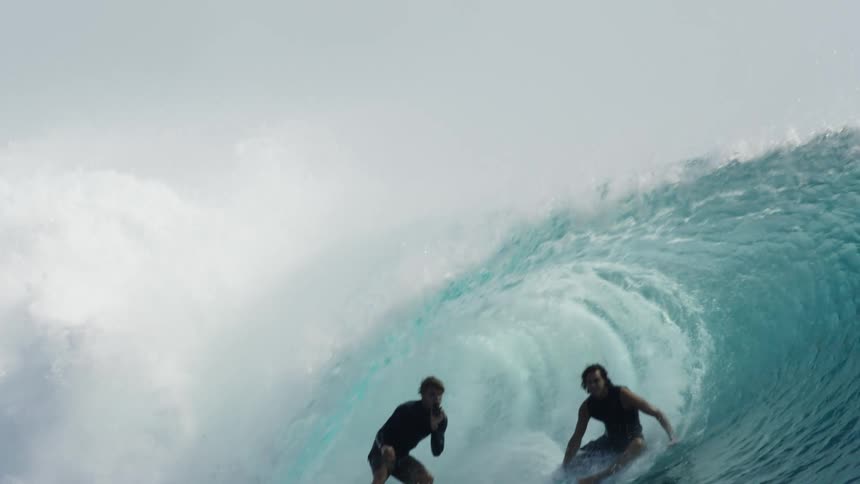 Two people are surfing the same wave
