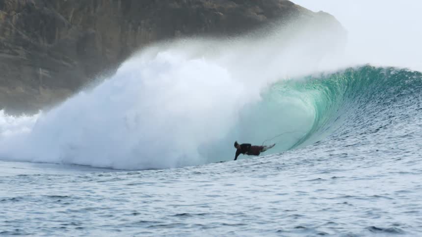 A man surfing a large wave falls down