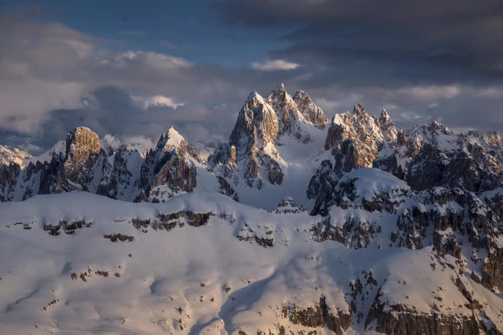 Clouds move over a mountain range covered in snow