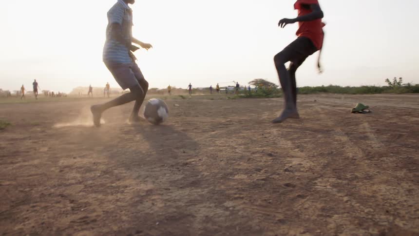 Three young kids kick a ball around