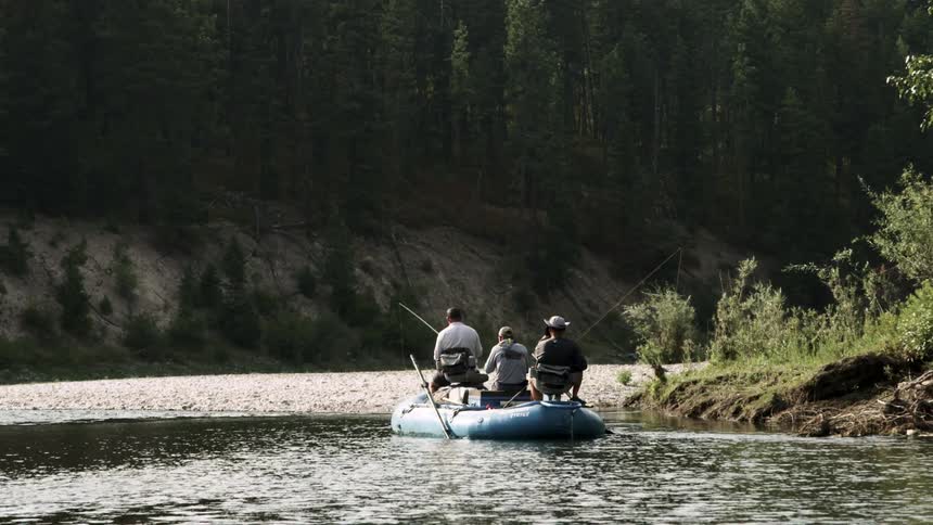 Three man sit on a small boat in the river fishing