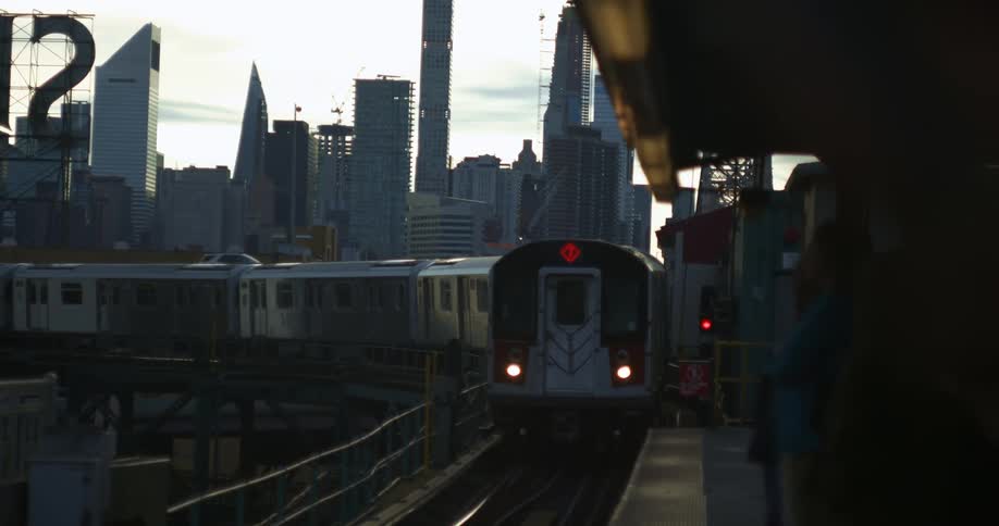 A train pulls up to a station as people wait