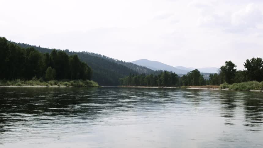 A river flows down from a mountain range and hilly terrain