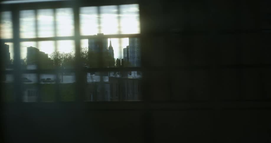 A city skyline is visible through the windows of a pedestrian bridge