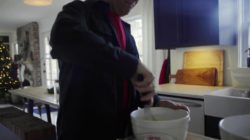 A man whisks eggs in a bowl in his kitchen at christmas time