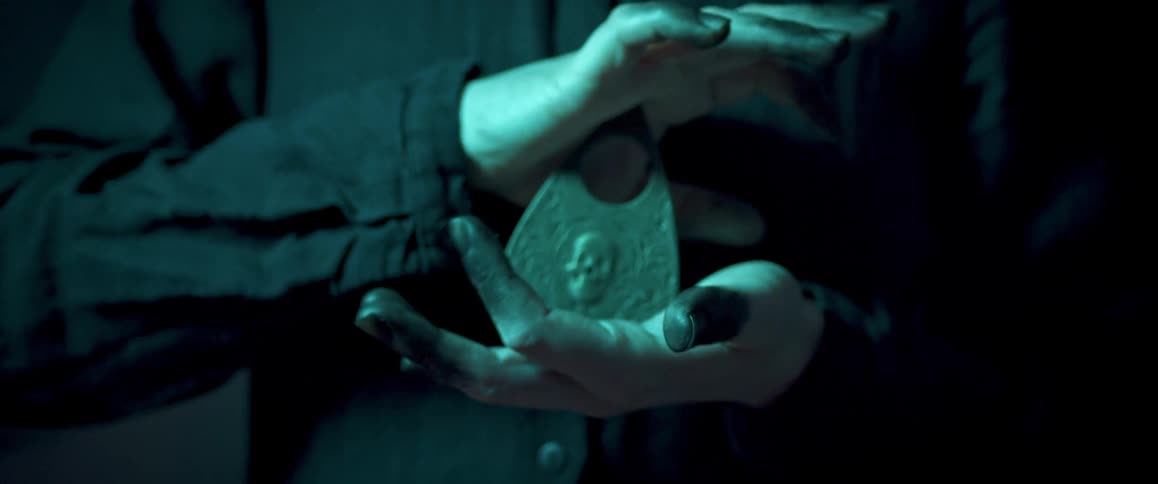 A person clasps a pointer for an ouija board