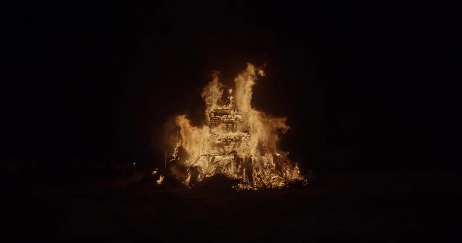 A statue of a man on a horse is set on fire at night
