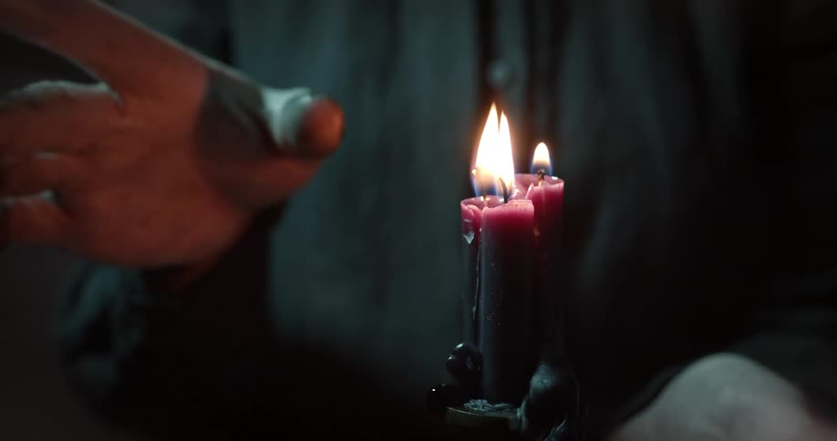 A person waves their hand around a candle