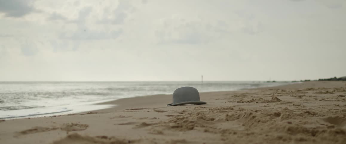 A hat lying on the sand of a beach just out of reach of the waves