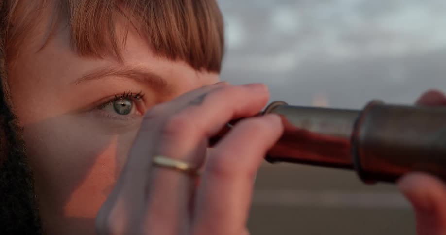 A woman outside looks through a telescope