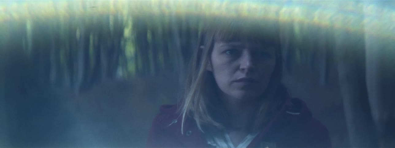 A white woman walks on a path through the woods