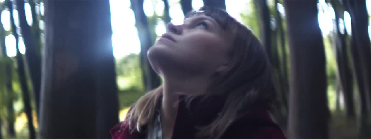 Woman stands in a forest looking up