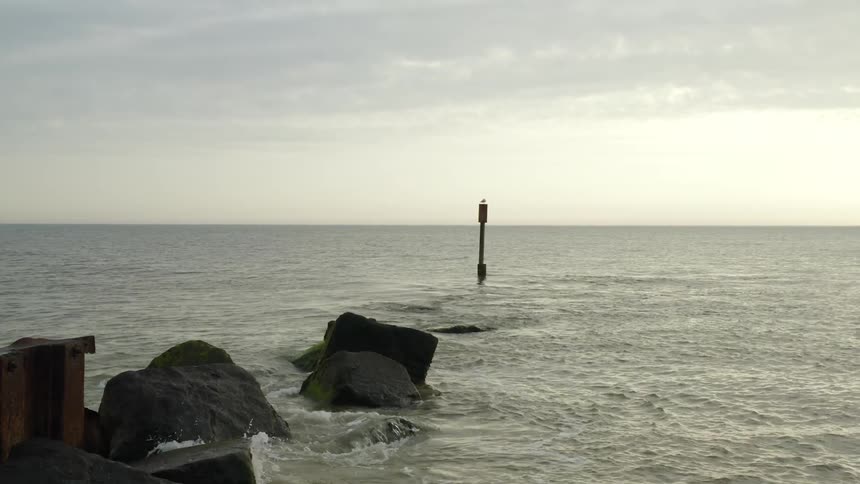 A beach marker in the sea near a rocky coastline