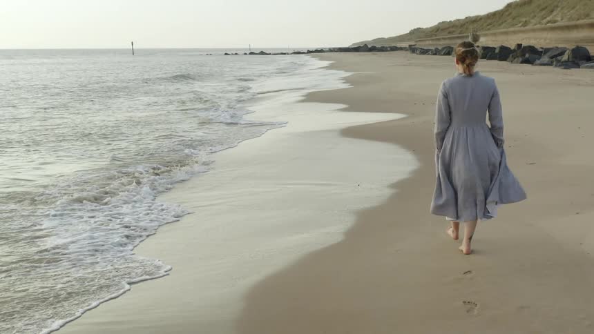 A young woman walks along the beach