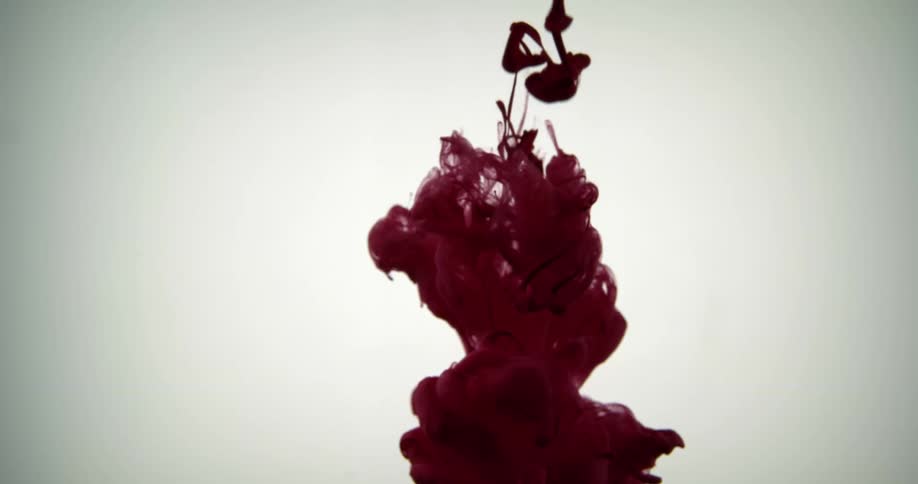 A maroon colored fluid spreads out in a clear solution