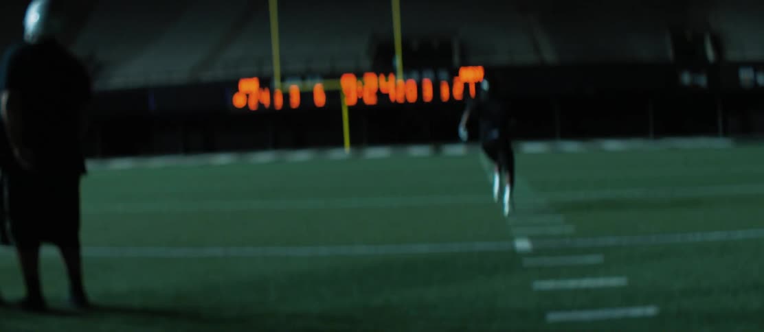 Football players doing drills in a football stadium at night