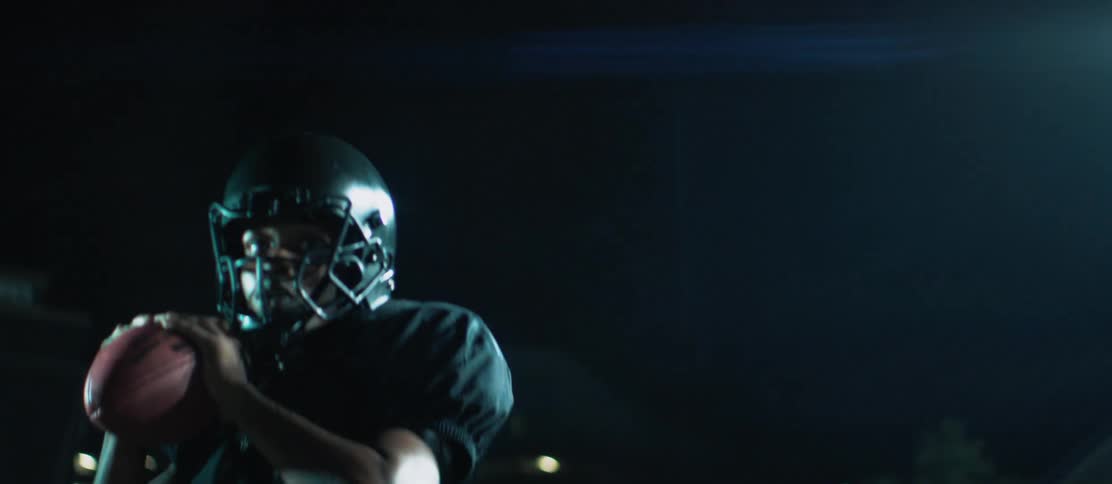 A man with a football helmet and uniform holding a football