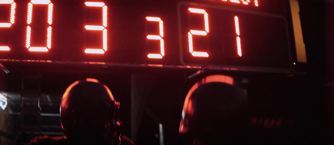 Two football players celebrate in front of an electronic scoreboard
