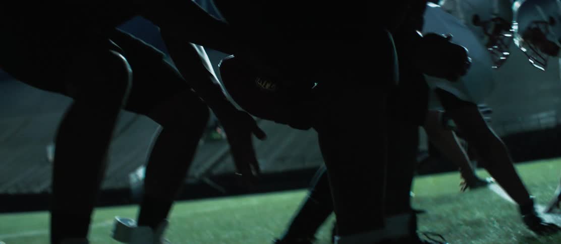 Football teams play in an empty stadium at night