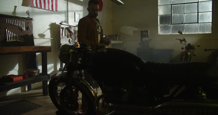Two male mechanics cut metal and repair a motorcycle at the garage