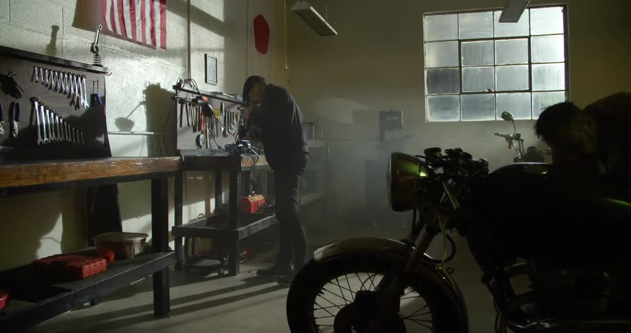 Man cuts metal on a workbench inside a workshop