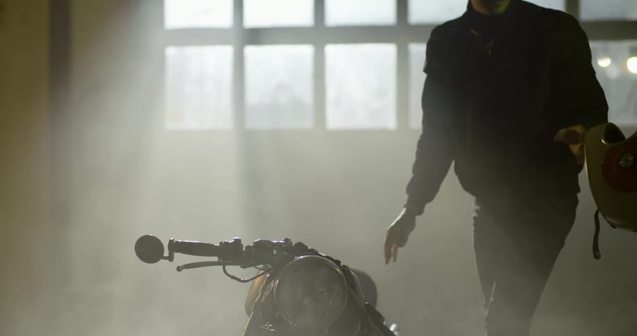 Man parks a motorcycle inside a dimly lit garage