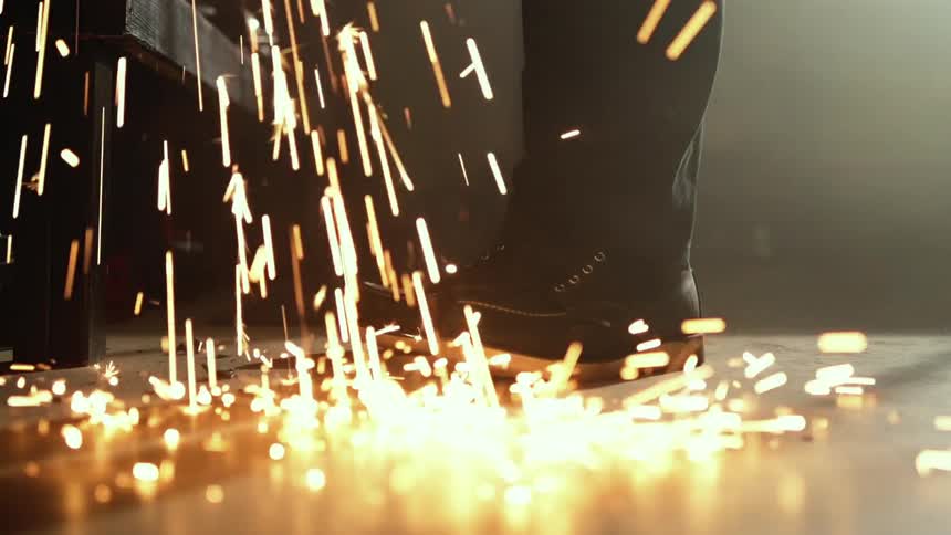 Sparks fall to the floor near a persons footwear