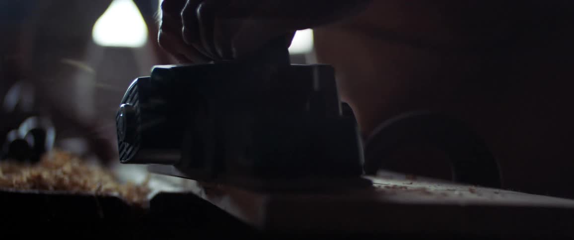 A man sanding wood inside