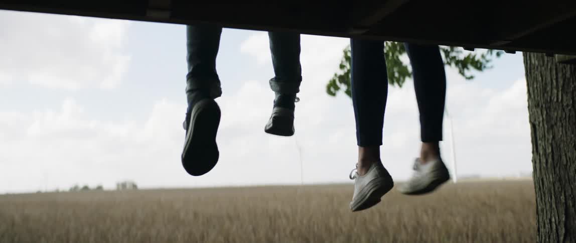 Two people kick their feet by the field