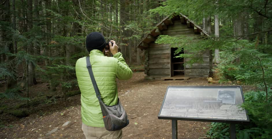 Photographer takes pictures of a cabin in the woods with a camera