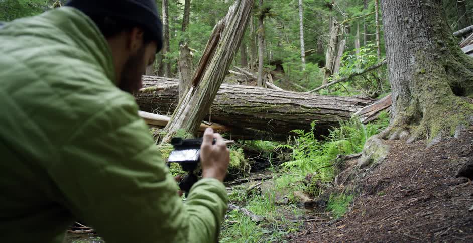 Photographer sets up a camera on a tripod in the forest