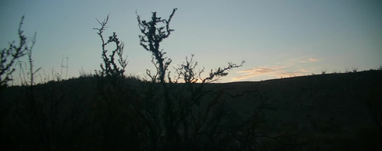 Clouds on top of hill are lit by sun below the horizon