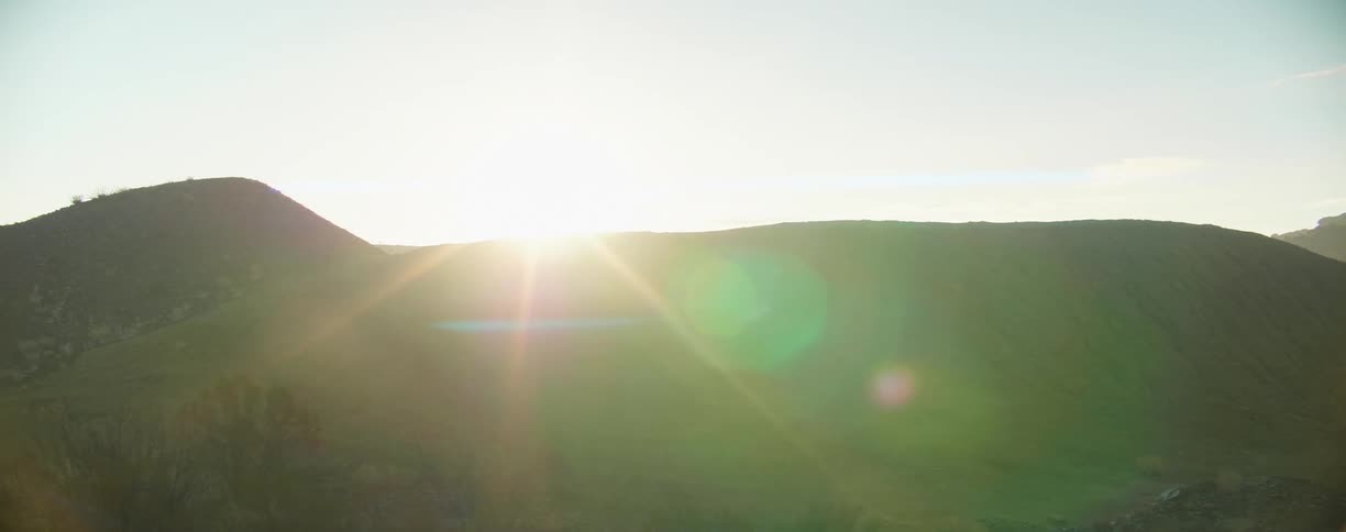 The sun is peaking up behind the hills