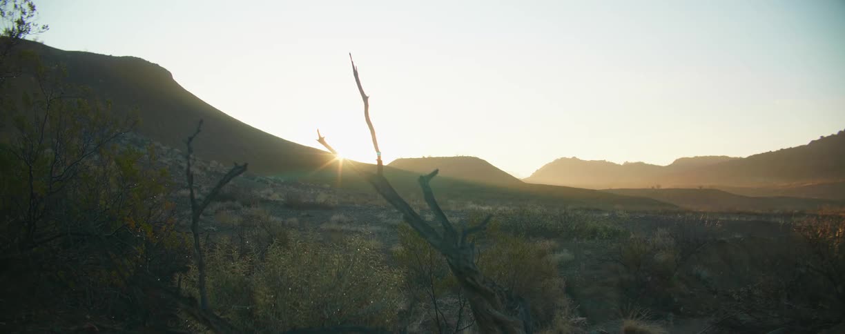 Sunlight filters through the mountains in the desert badlands at sunset