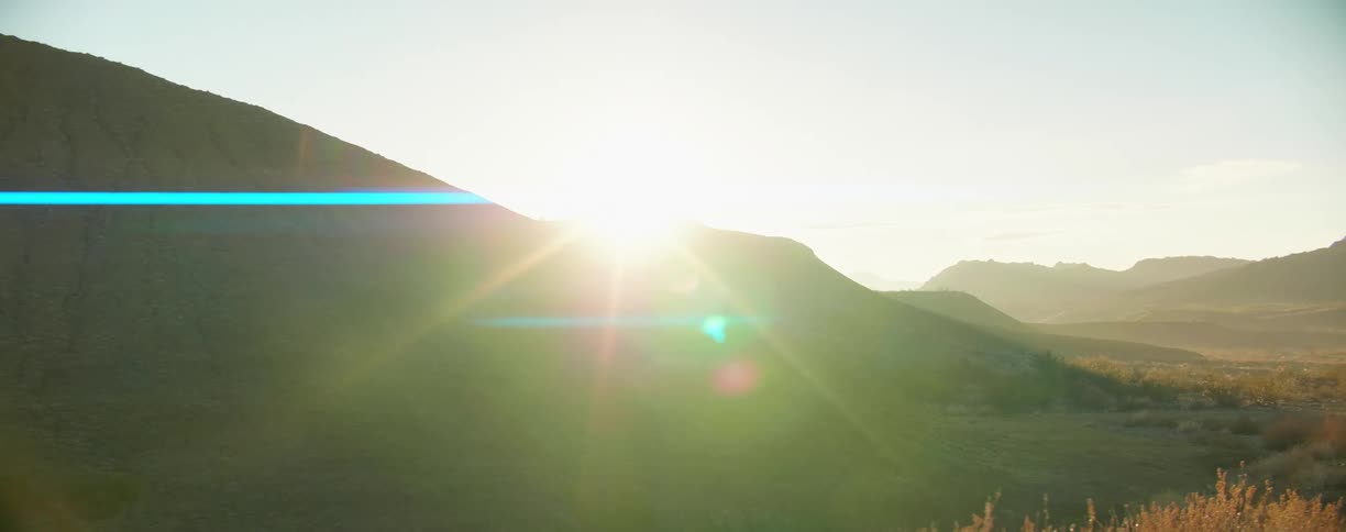Sunset sunlight filters through the mountaintops in the badlands desert