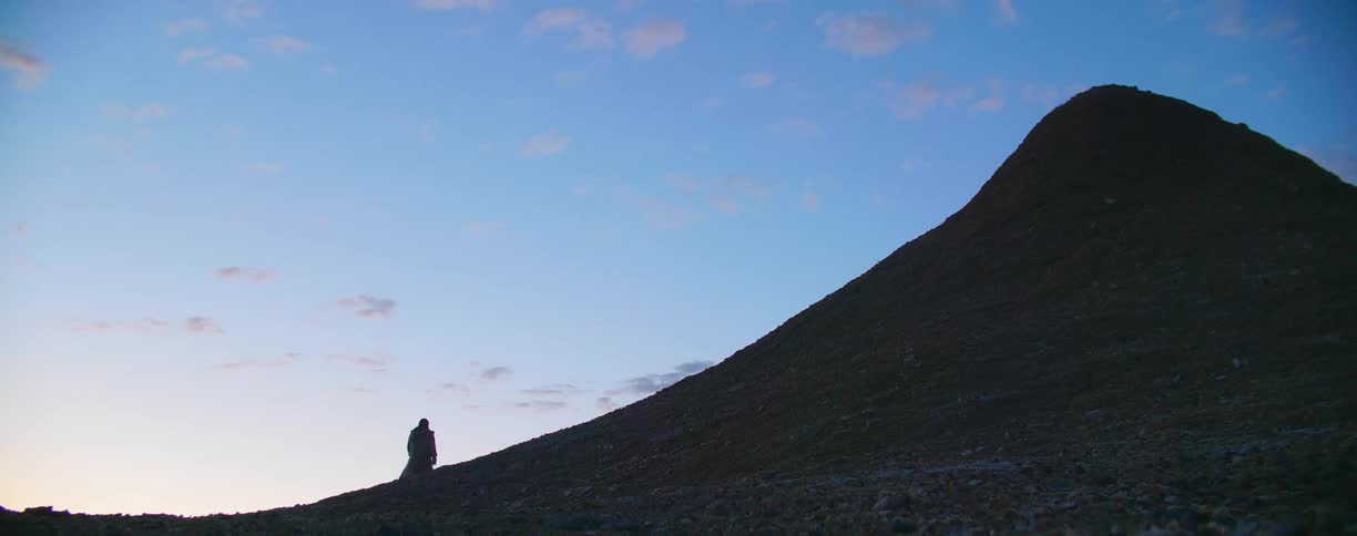 A man walks over a hill