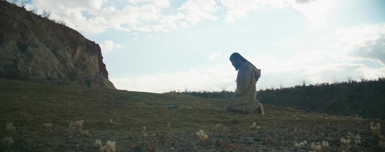 A man kneeling outside and praying