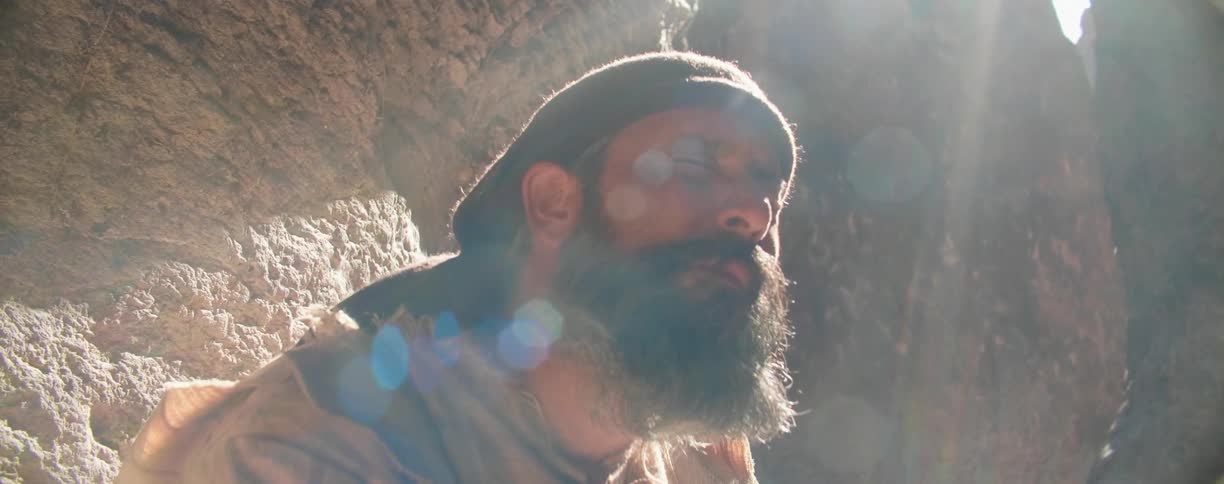 The sun shines on a white man with his eyes closed while he talks to himself
