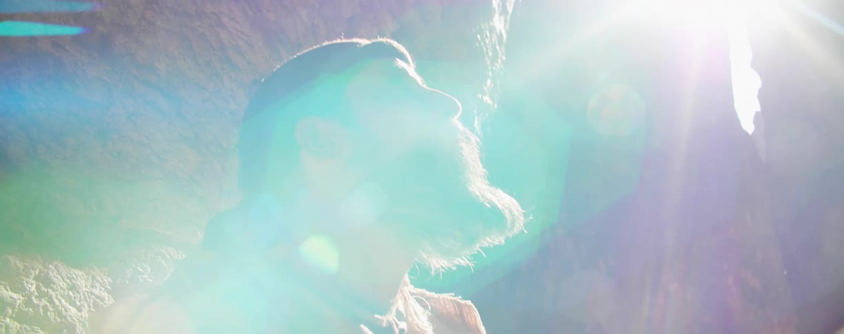 A man leaning against a canyon looks up at the sky