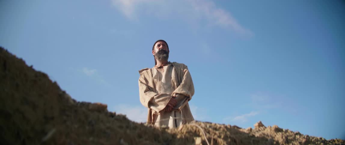 Meditative bearded man stands in the desert at morning
