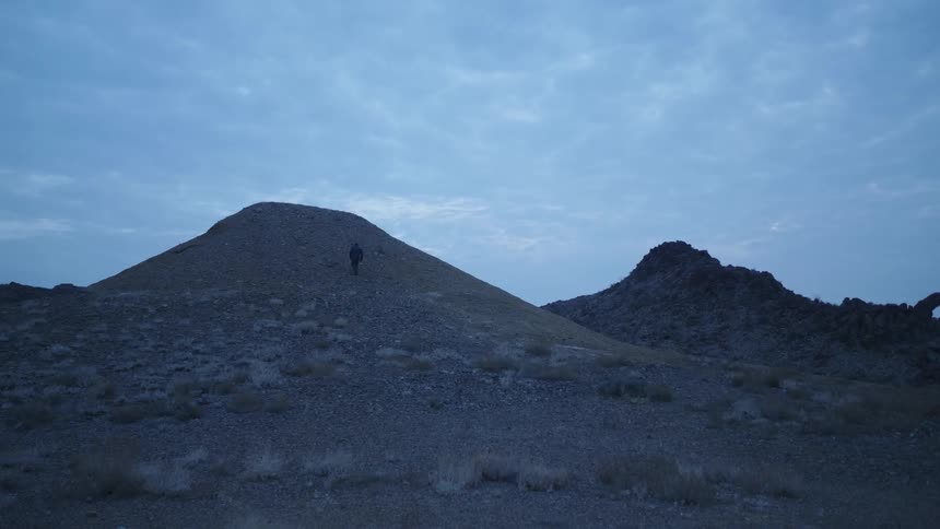 Man runs up a hill in a desert at morning
