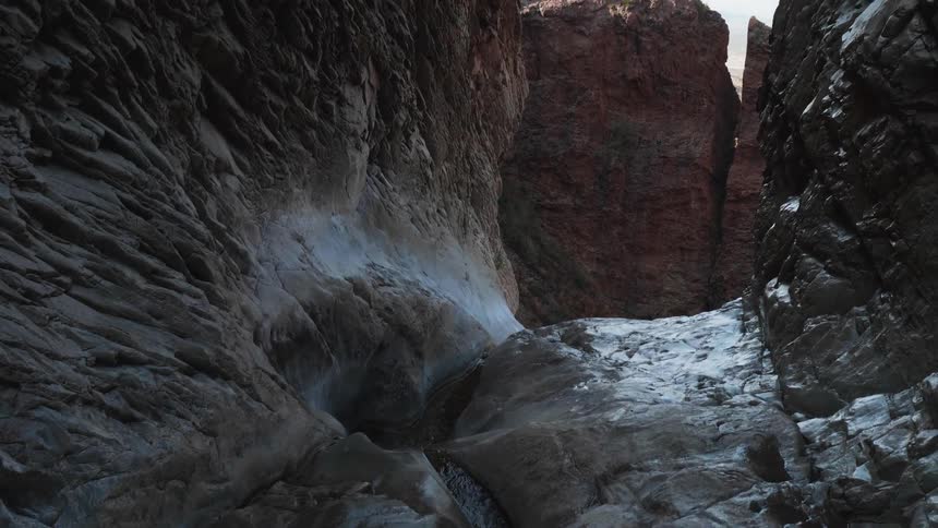 Water runs in a small creek between formations in a canyon