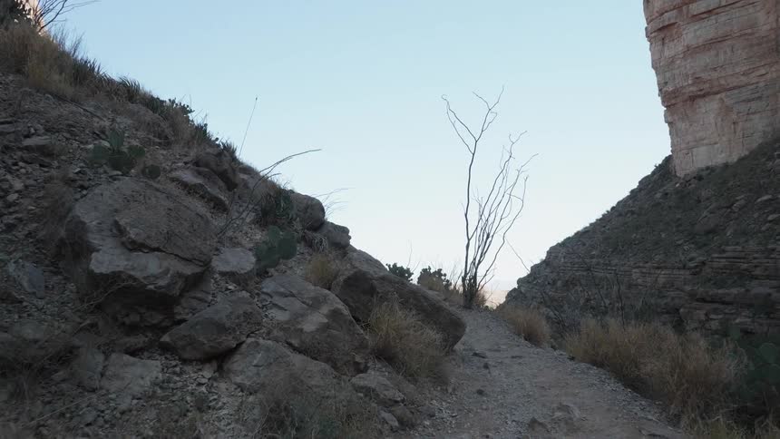 A narrow gravel path on the side of a mountain covered in stone